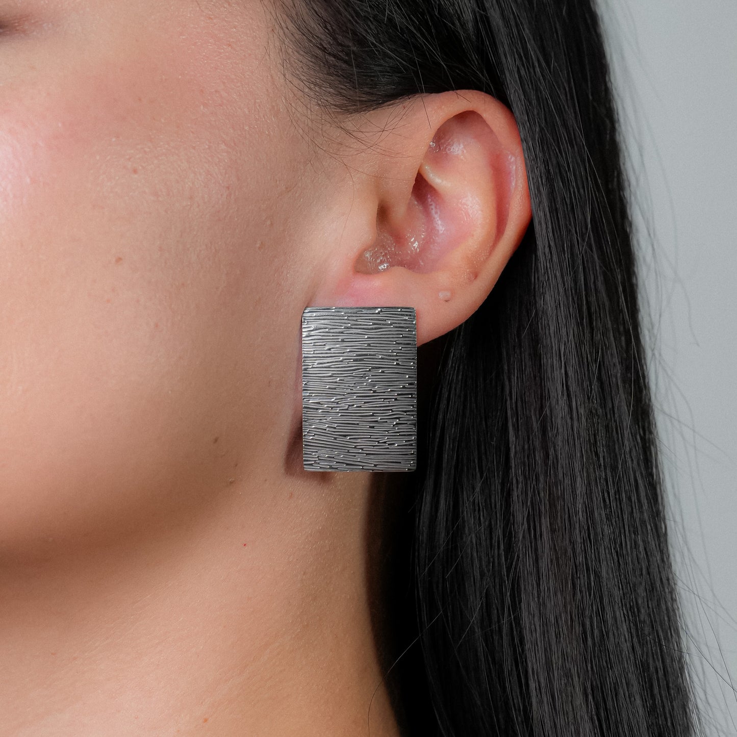 Arete plateado cuadrado con textura lineal