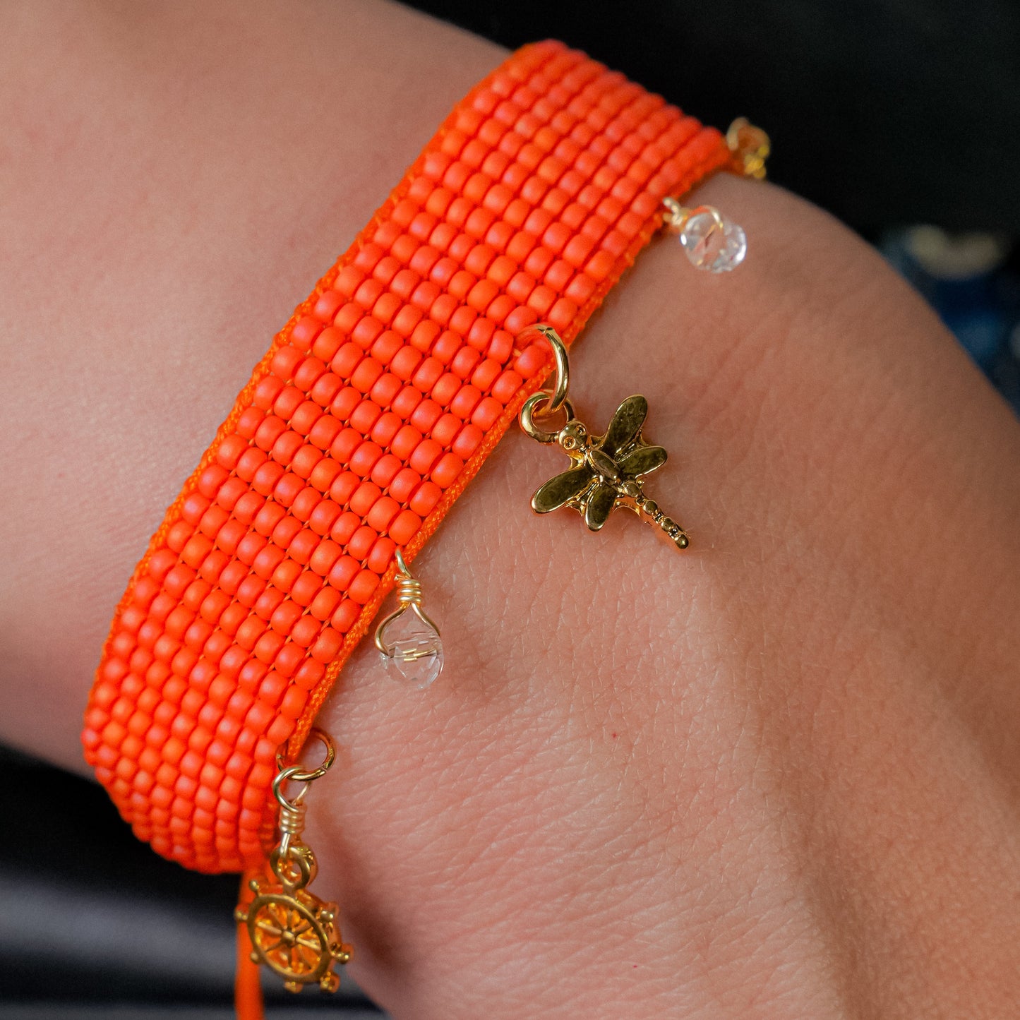 Pulsera tejida naranja con dijes colgantes