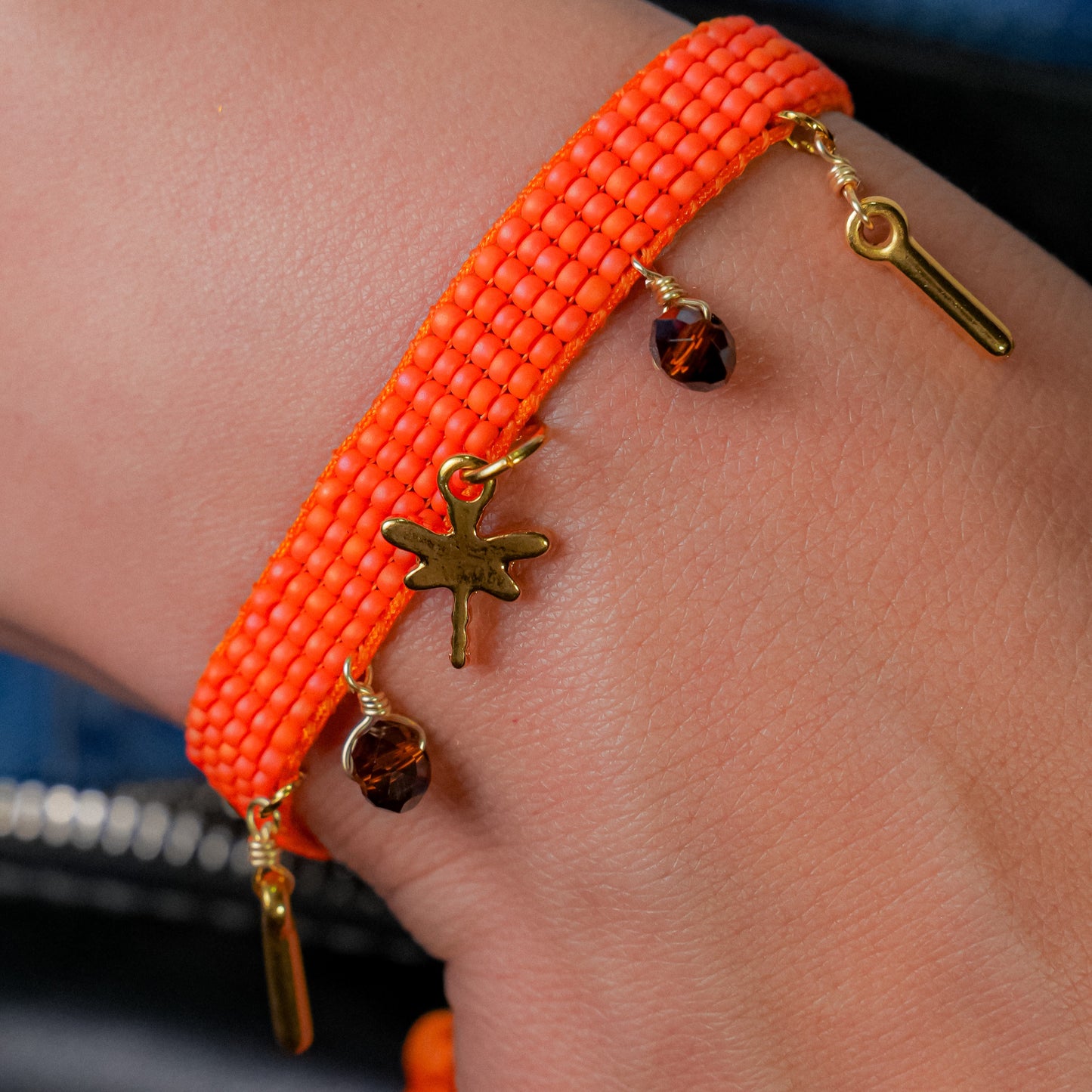 Pulsera tejida naranja con dijes colgantes