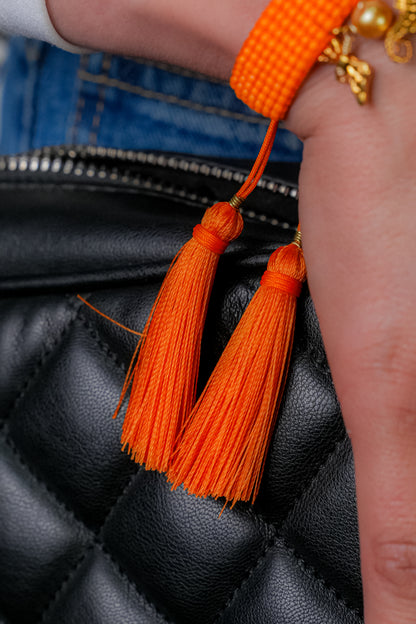 Pulsera tejida naranja con dije de caballo de mar