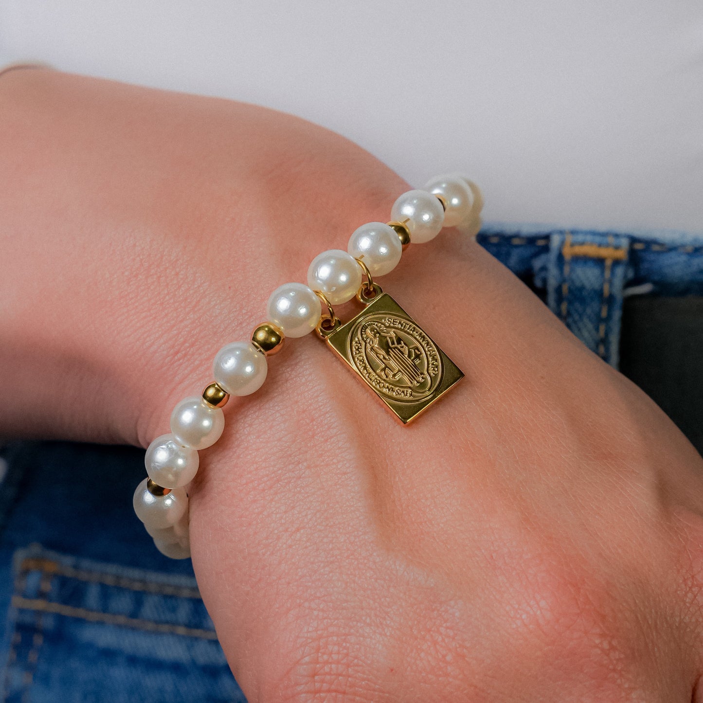 Pulsera en perla con dije religioso